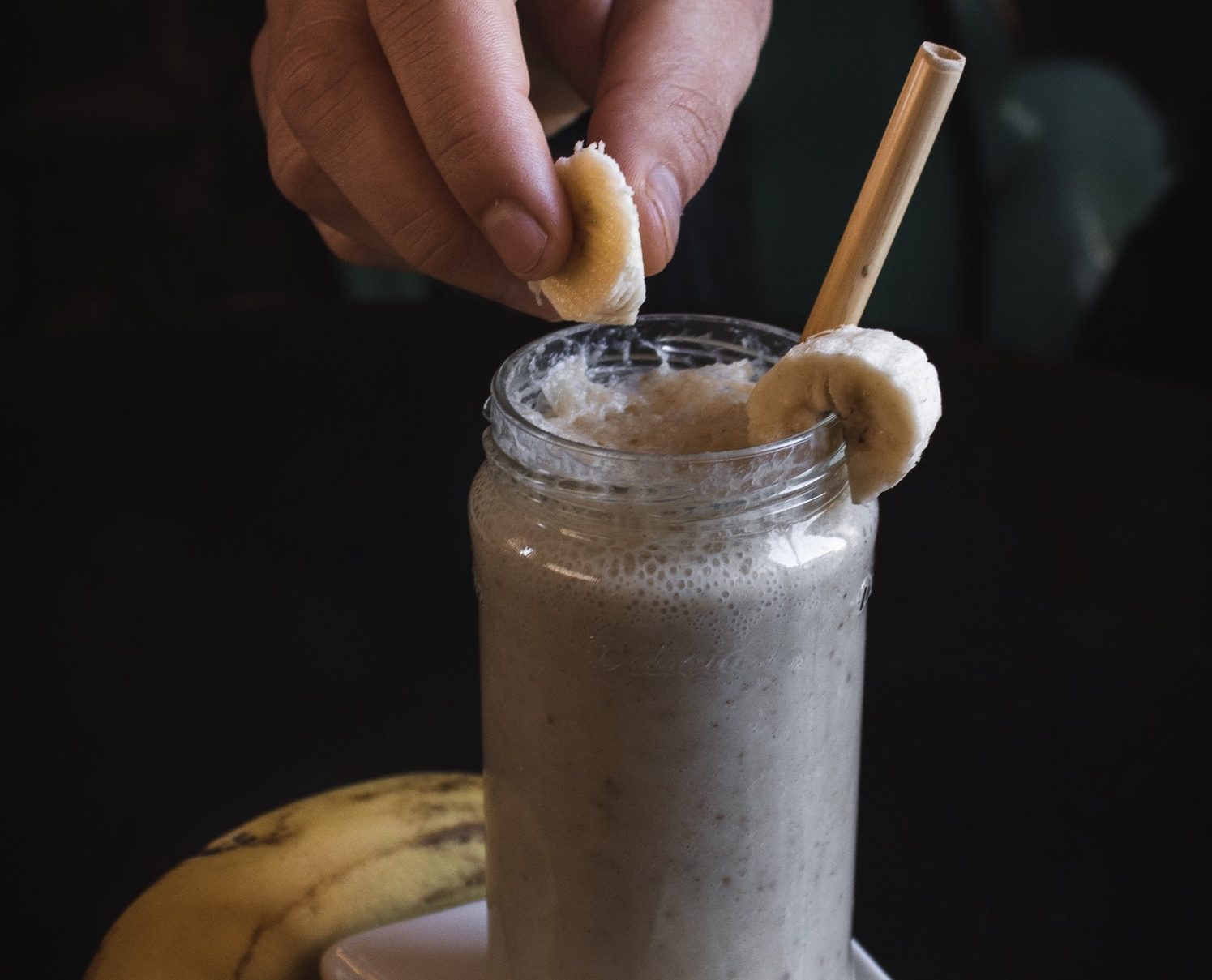 milkshake with a hand putting a banana topping on the side