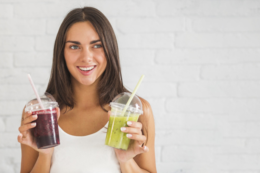woman holding two cup of fruit shakes